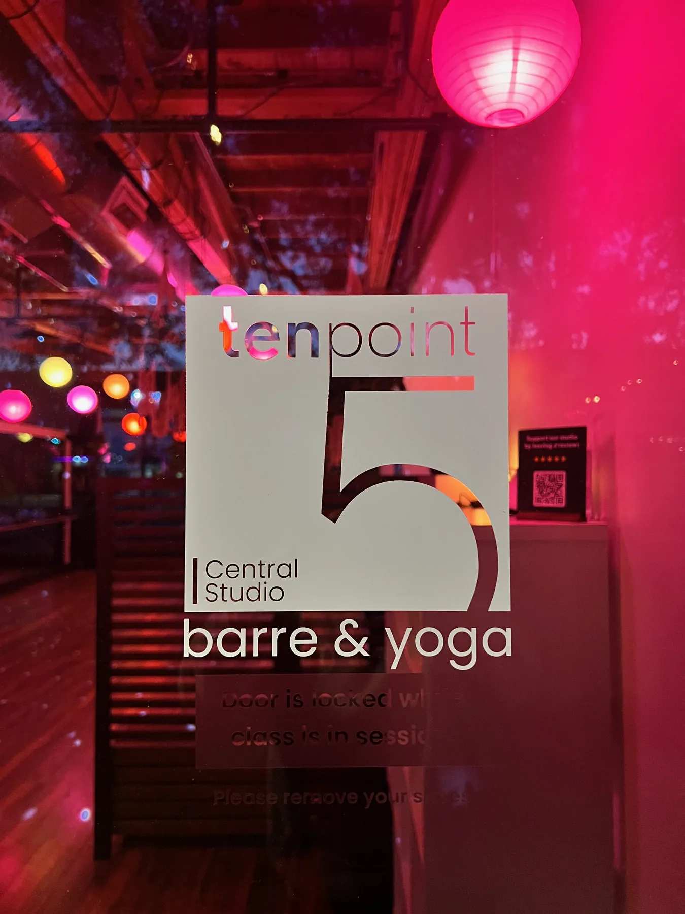 TenPoint5 Central Studio front signage glowing pink at night — 'tenpoint5 Central Studio barre & yoga' on a glass door with a paper lantern overhead