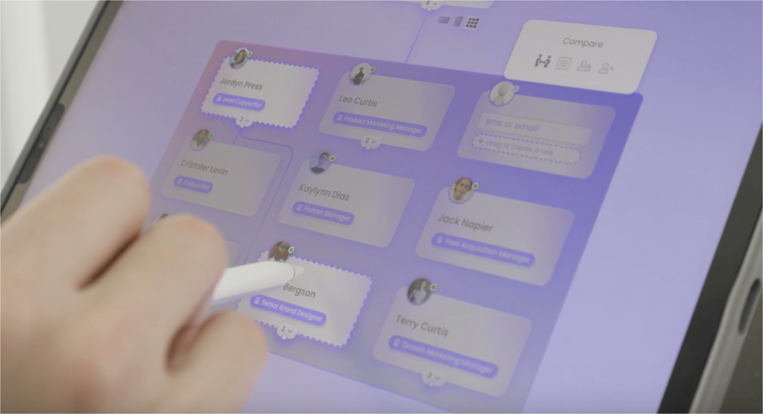 Tablet vision frame — a hand using an Apple Pencil on an iPad to manipulate org-chart cards in the glassmorphism interface